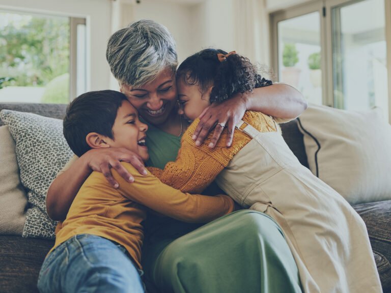 Bienfaits de la Sophrologie. Grand-mère et enfants heureux sur un canapé profitant de moments de qualité