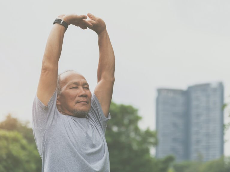 homme âgé pratiquant un exercice de relaxation dynamique dans un parc