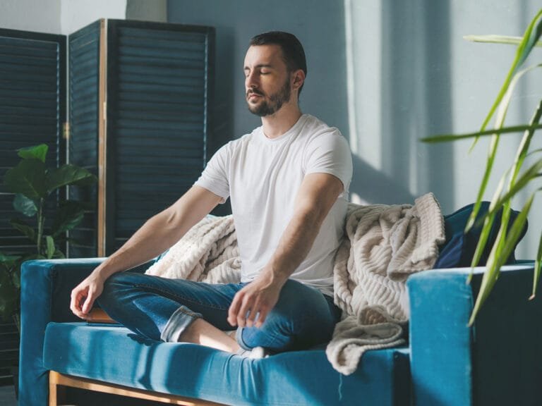 meditation - jeune homme meditant sur un canapé respirant profondément